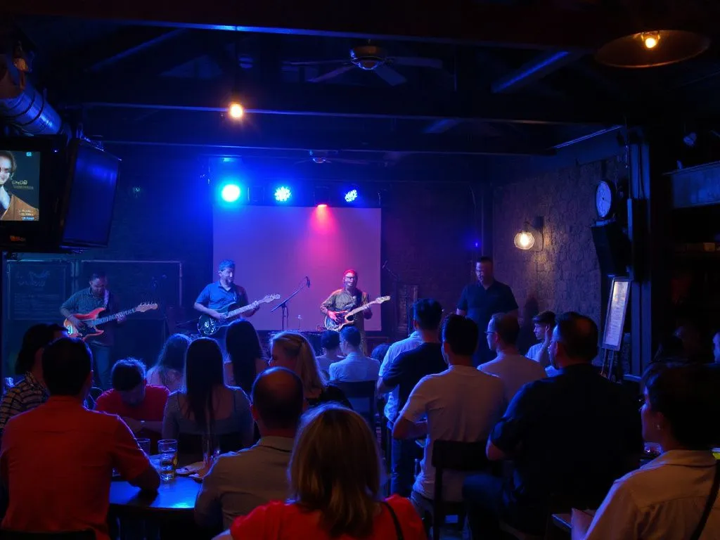 Relaxed bar setting in Ubud with live band playing, featuring reggae and blues musicians on stage with an audience of diverse patrons enjoying laid-back atmosphere and dim lighting